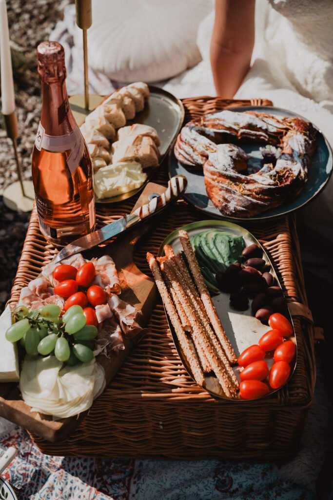 Close view of a picnic with fruit, pastries, flowers and a bottle of rosé.