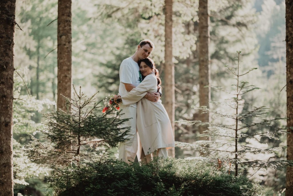 Couple embracing among sunlit trees in a forest.