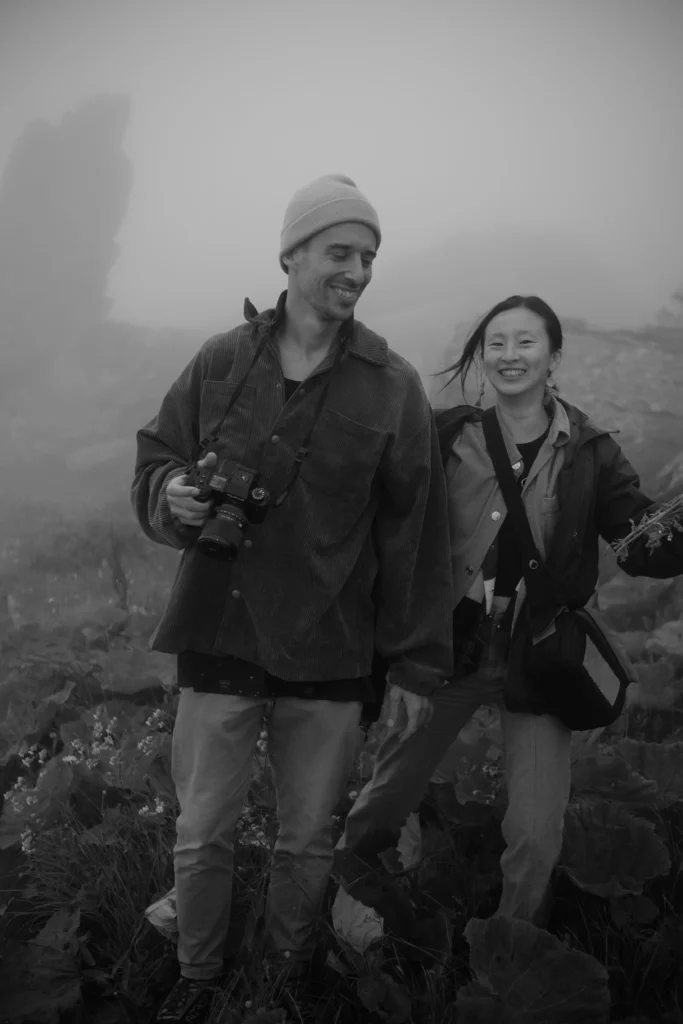 Black-and-white portrait of Elias and Wendy with cameras in the mountains.