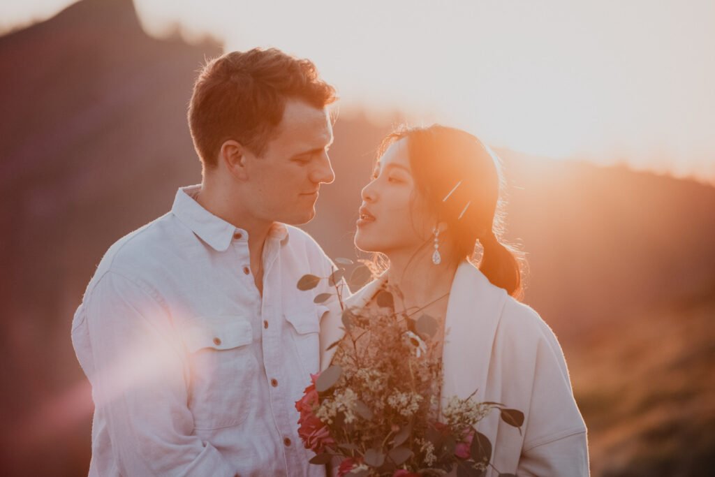 Couple smiling at each other with the low sun glowing behind them.