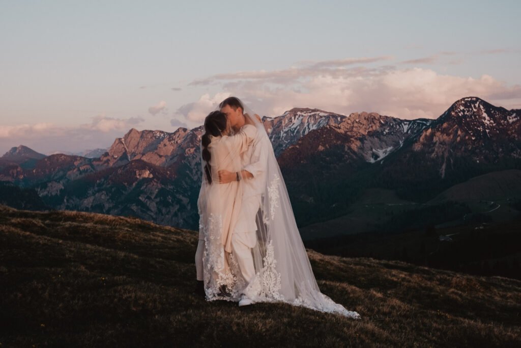 Couple embracing on a mountain meadow in soft evening light.