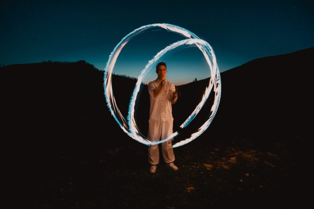 Groom surrounded by circular sparkler trails against the night sky.