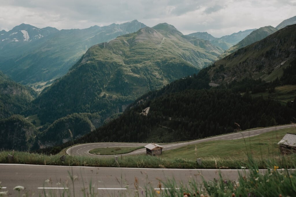 Winding alpine road overlooking layered green mountain ridges.