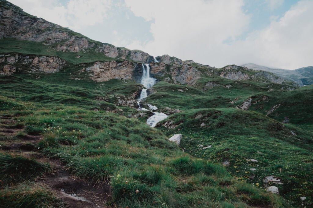 Couple in wedding attire on a green alpine slope.