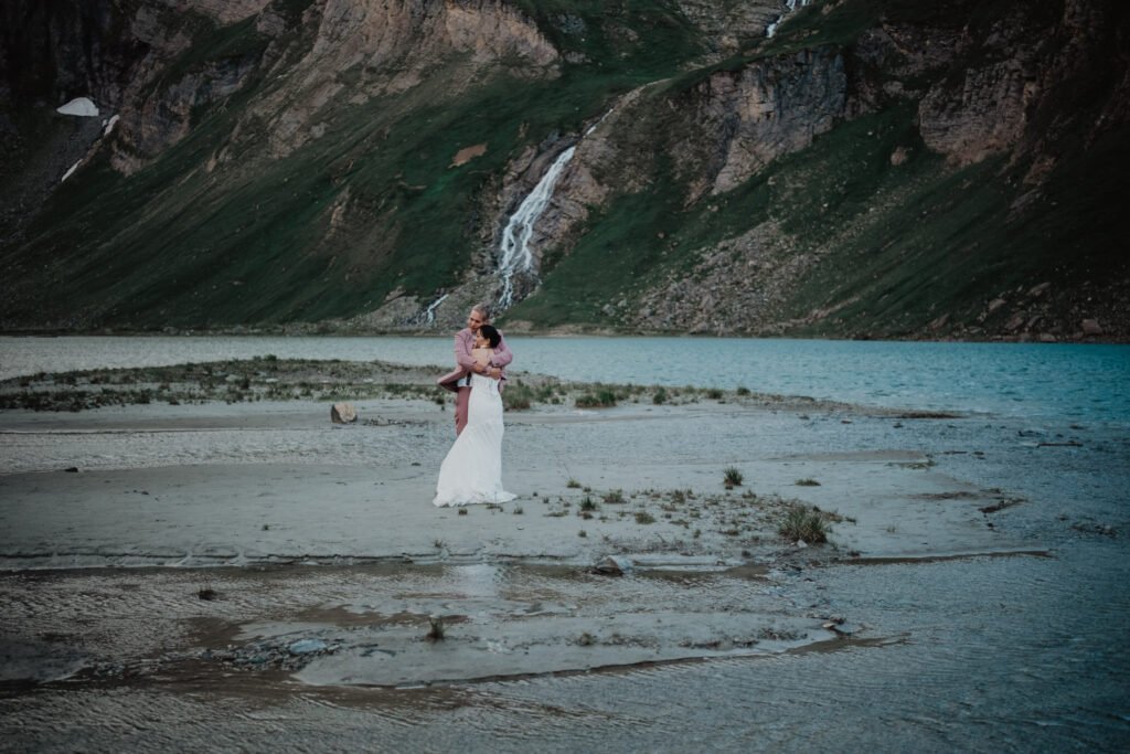 Couple embracing on the shore of a turquoise alpine lake.
