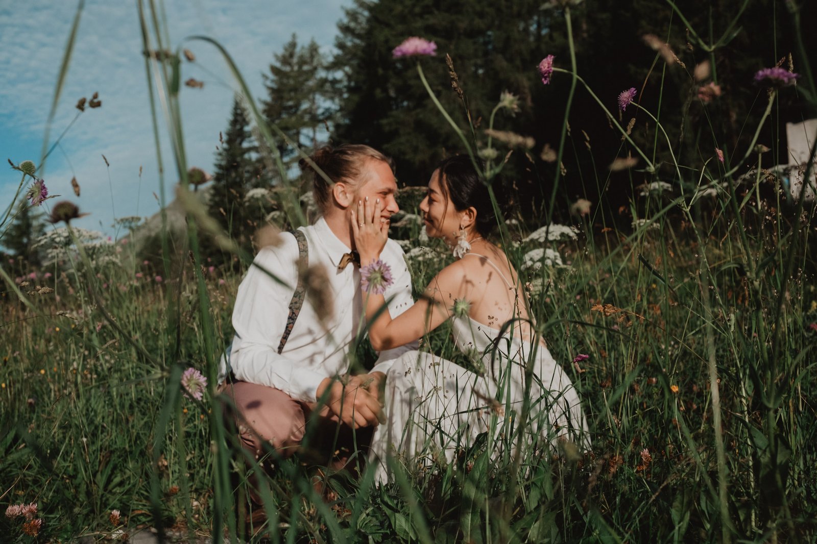 Couple sitting together among wildflowers in an alpine meadow.