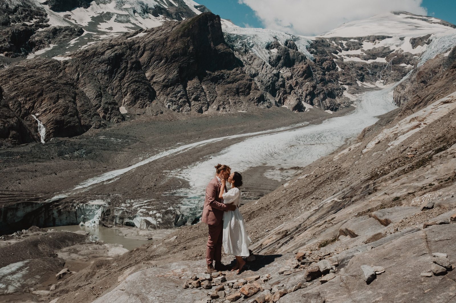 Paar steht gemeinsam auf Felsen neben einem Gletscher.