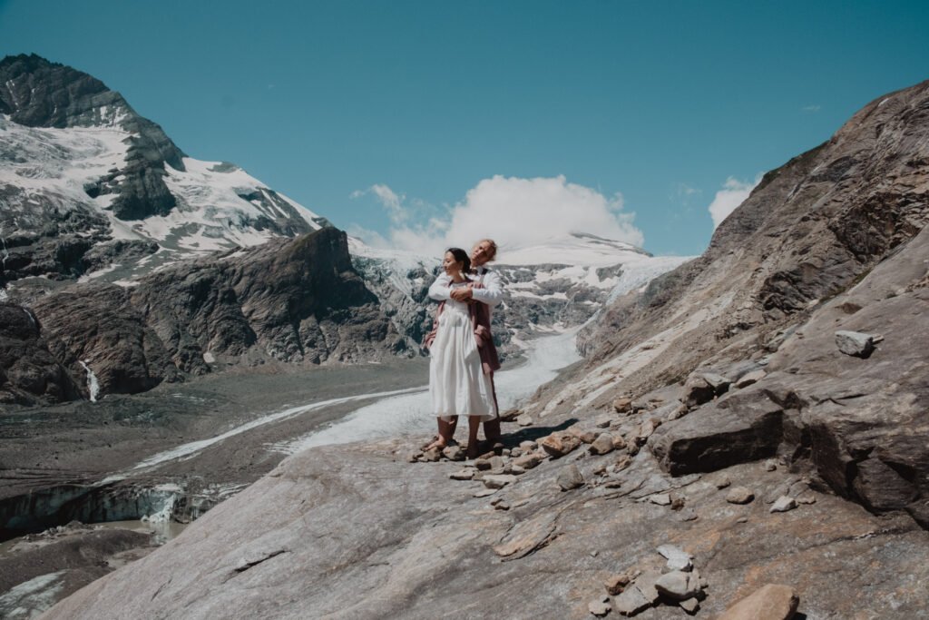 Couple standing together above a glacier valley.