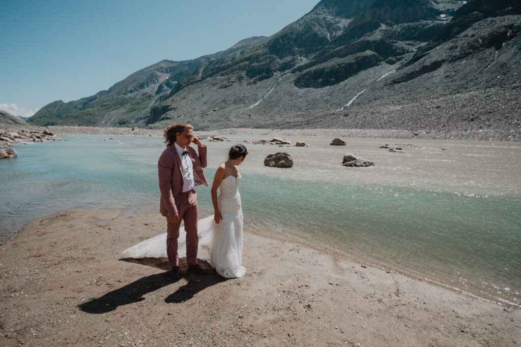 Couple walking together beside a turquoise alpine lake.