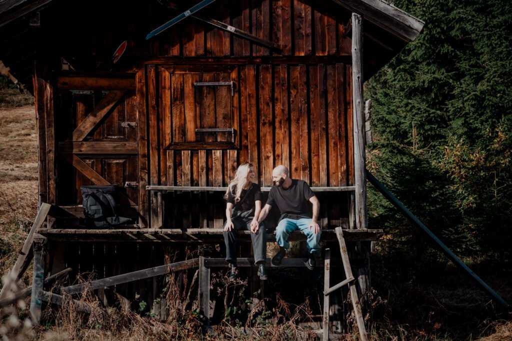 Couple sitting together on a mountain hut porch.