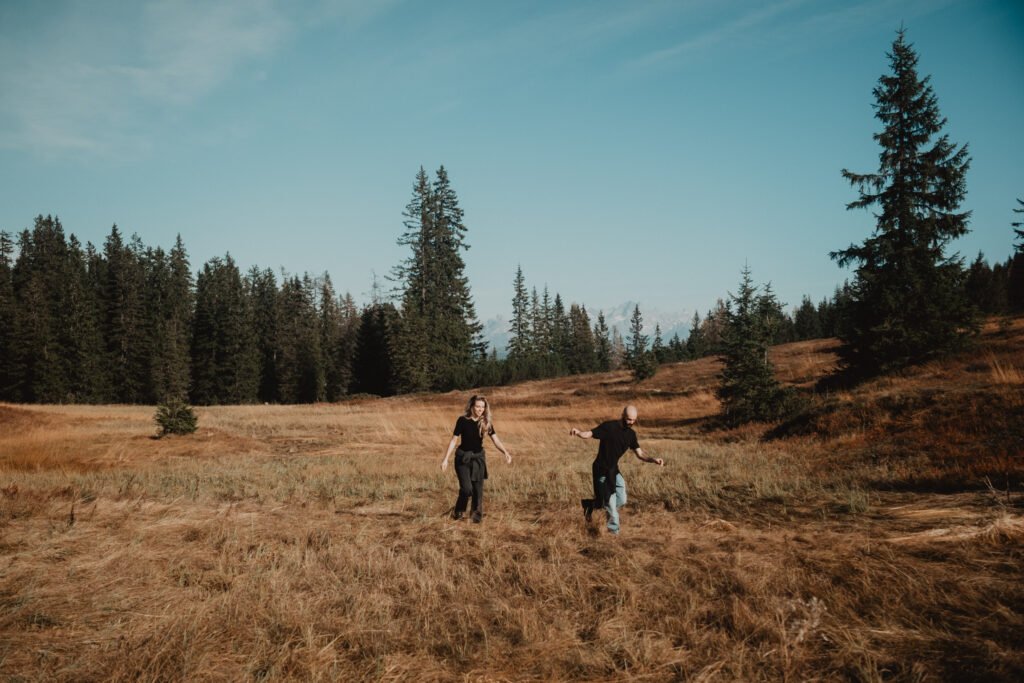 Couple walking together across a broad mountain meadow.