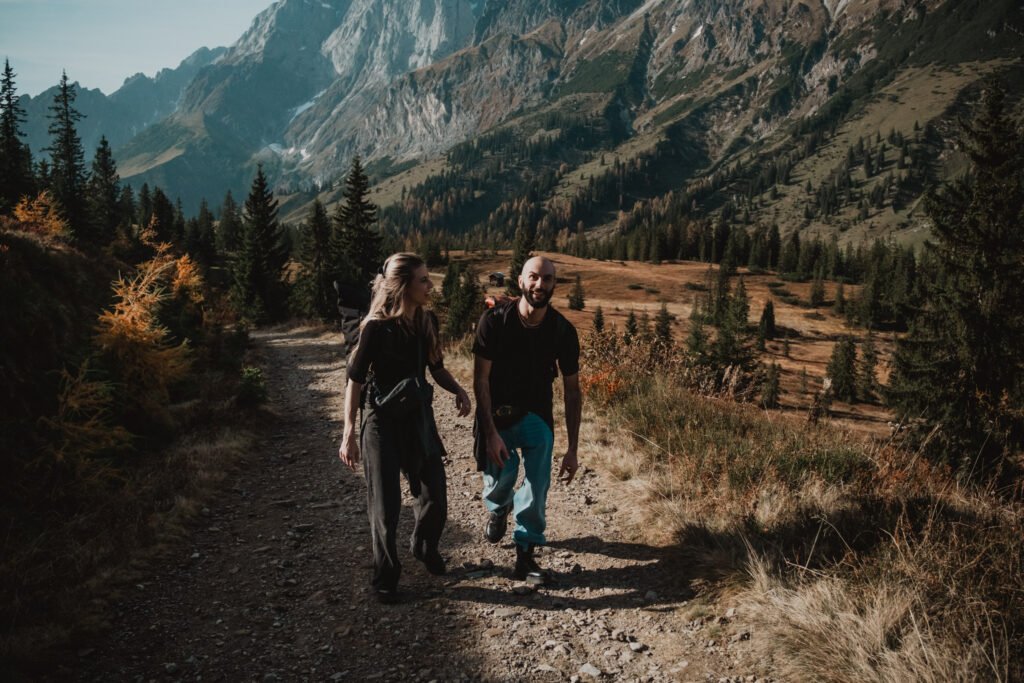 Couple walking up a mountain trail through autumn meadows.