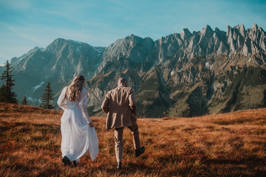 Couple holding hands and walking through a mountain meadow.