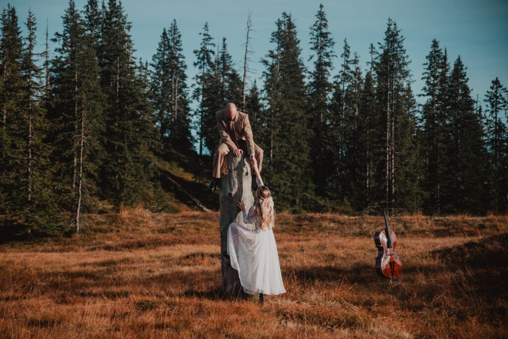 Couple beside a tree stump with a cello case on the ground.