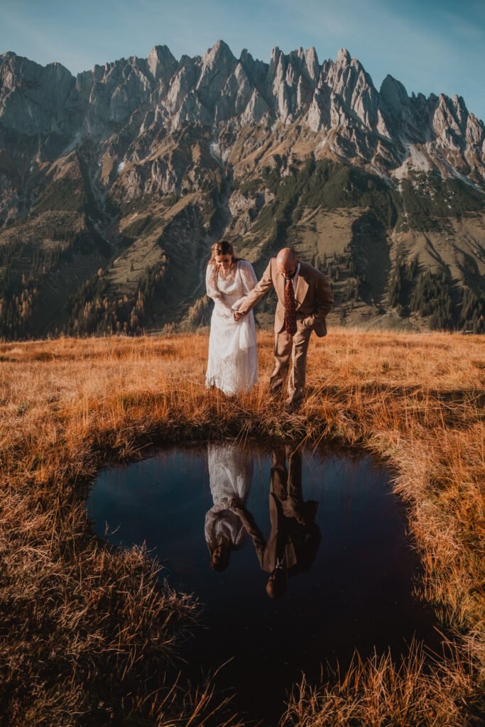 Couple reflected in a still mountain pond.