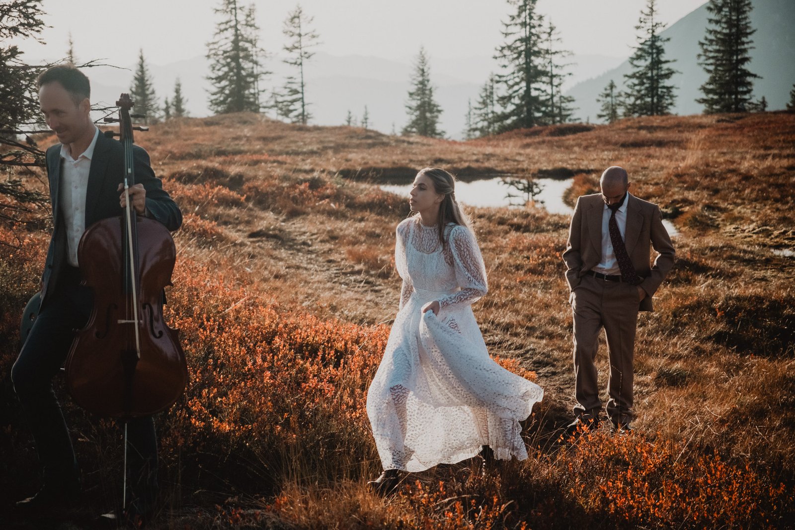 Paar geht über eine Wiese; im Vordergrund spielt ein Cellist.