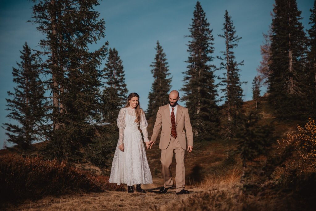 Couple standing together among autumn trees.
