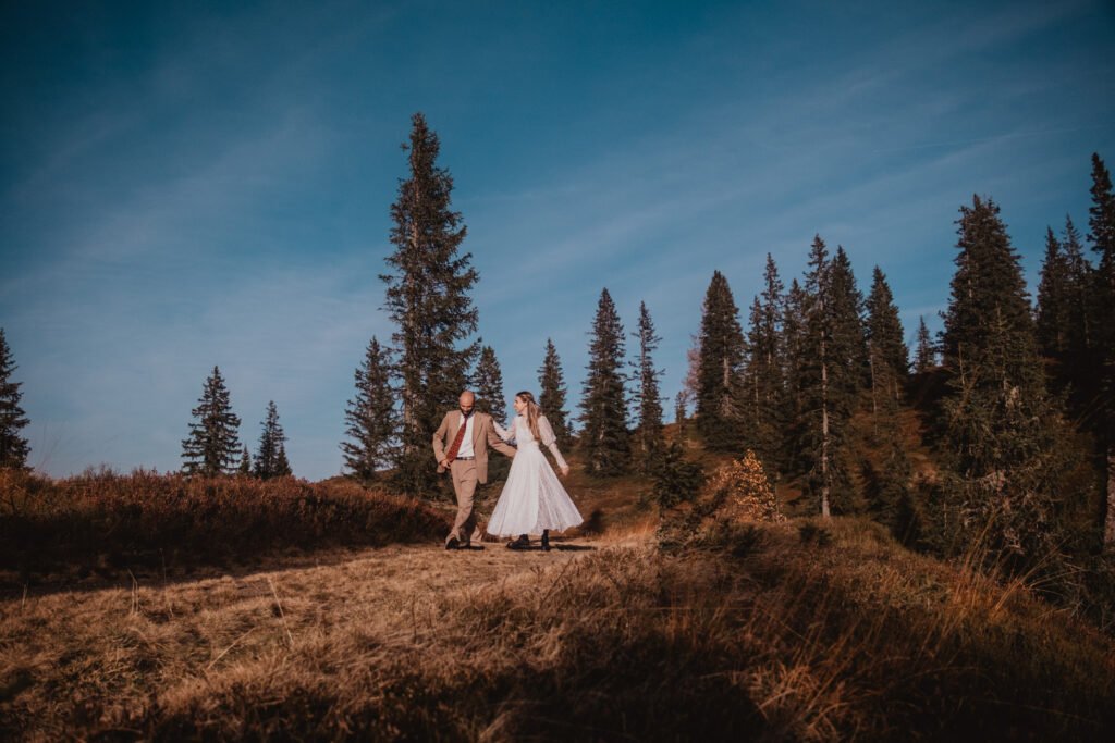 Couple in wedding clothes walking through an autumn alpine meadow.