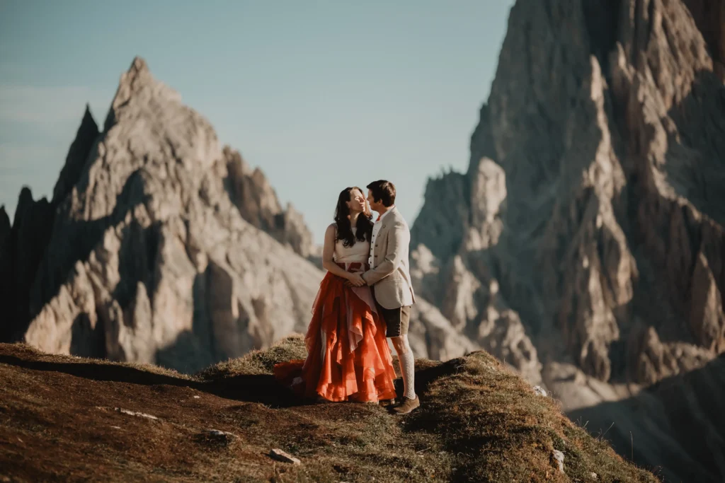 Bride in an orange skirt embracing her partner in the mountains.