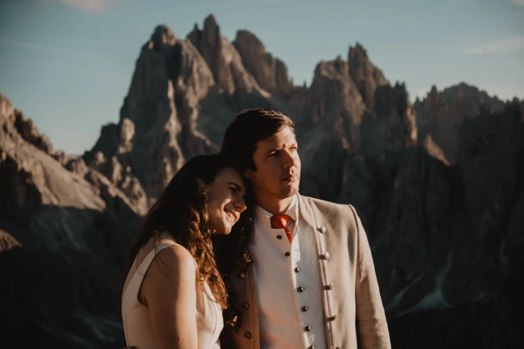 Couple resting together beneath mountain peaks.