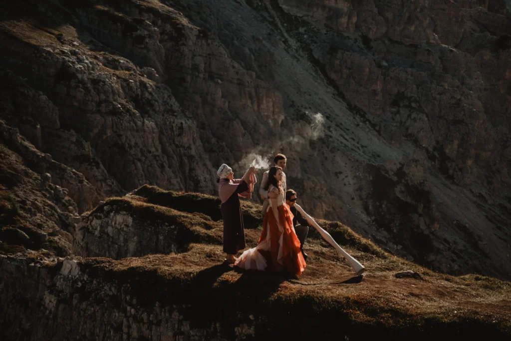 Couple with a long flowing dress during a ceremony on a mountain ridge.