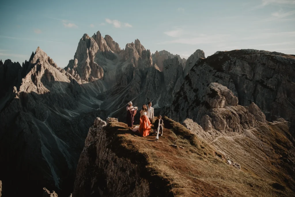 Intimate ceremony with a couple and their companions on a narrow mountain ridge.