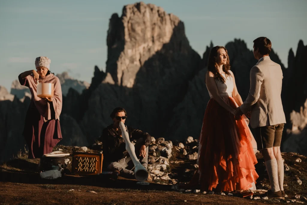 Mountain ceremony with a couple, celebrant and musician on the ridge.