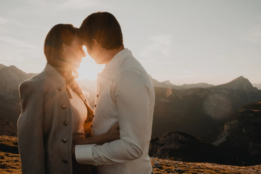 Couple touching foreheads with sunlight between them.