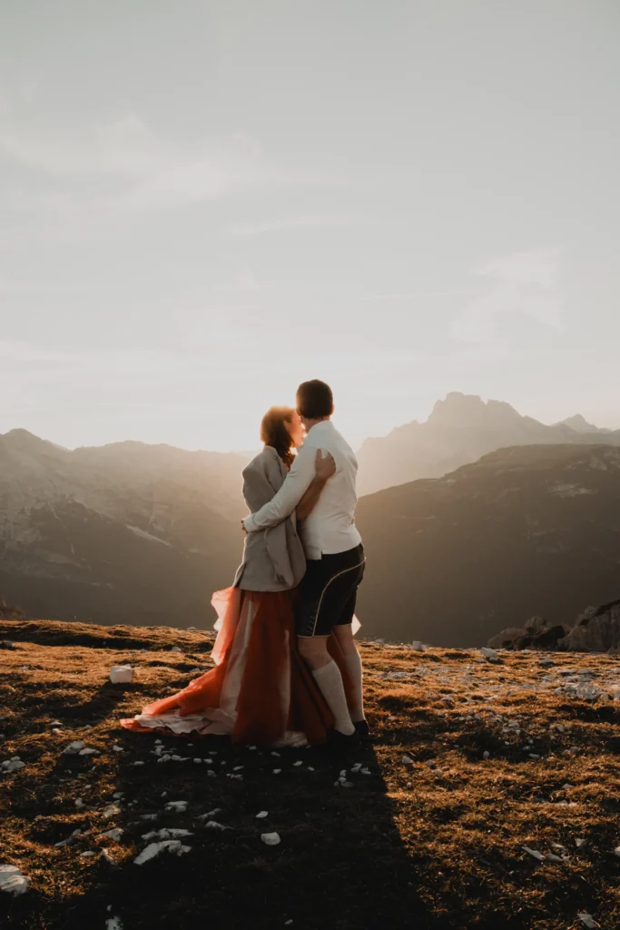 Couple embracing on a rock at sunset.