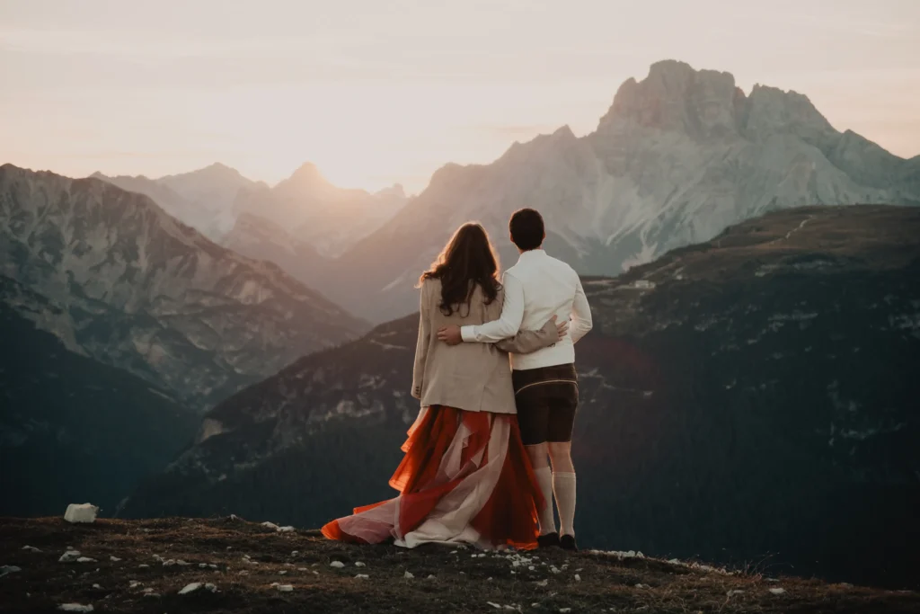 Couple with their arms around each other watching the sunset.