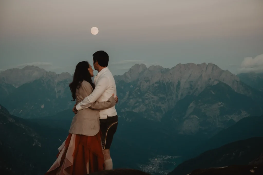 Couple embracing above a blue mountain valley in the evening.