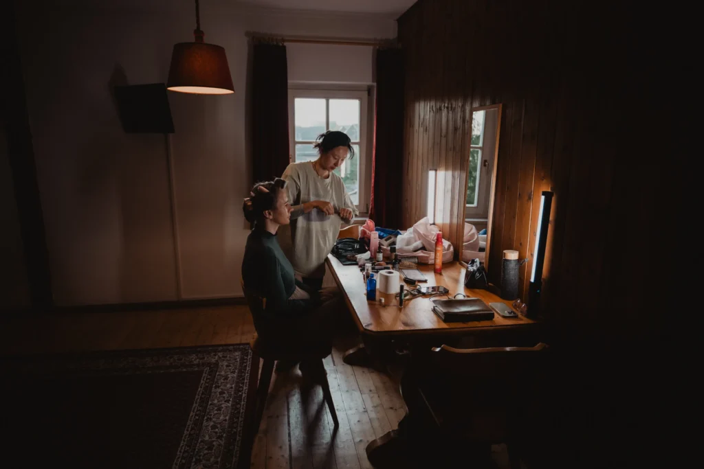 Bride having her hair styled at a dressing table.