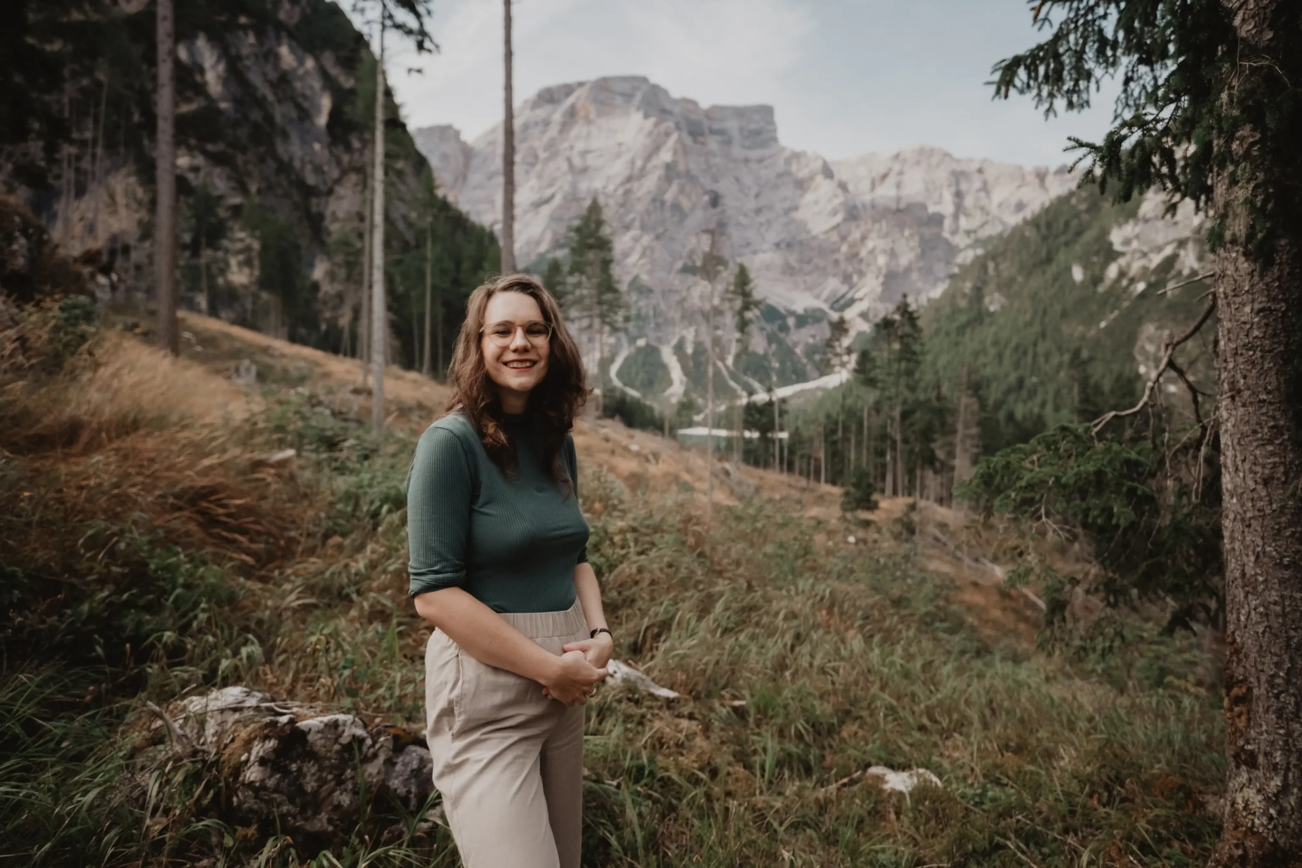 Frau lächelt im Wald neben einem Bergsee.