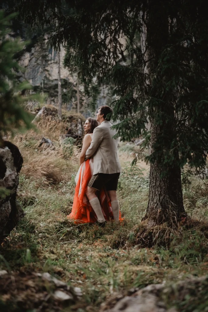 Couple walking through the forest in their wedding clothes.