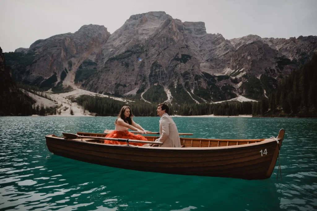 Couple sitting opposite each other in a wooden rowing boat.