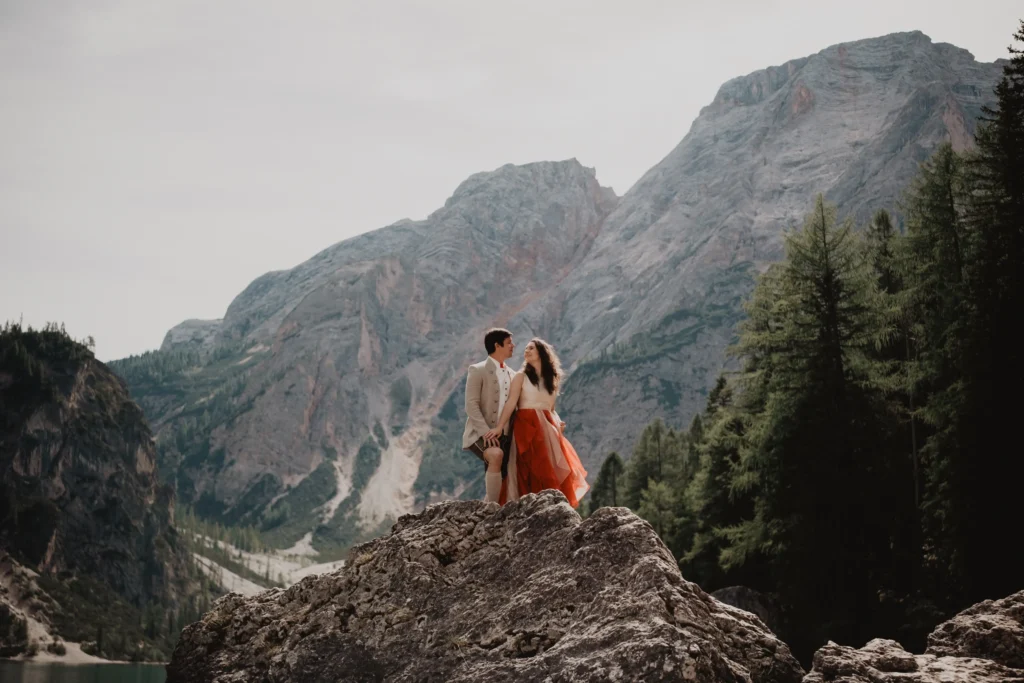 Couple standing together on a lakeside rock.