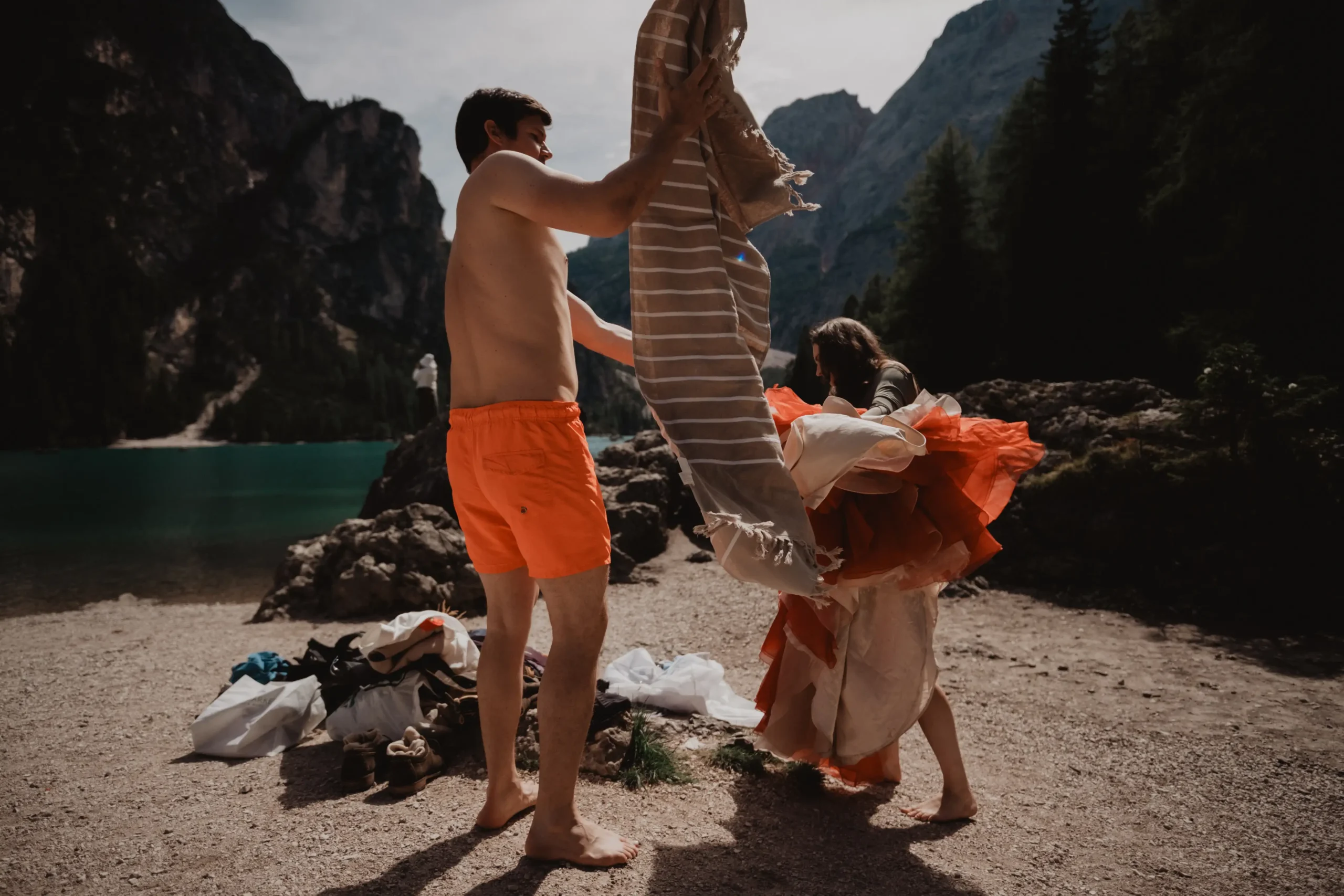 Paar zieht sich am See vor dem Schwimmen aus der Hochzeitskleidung um.