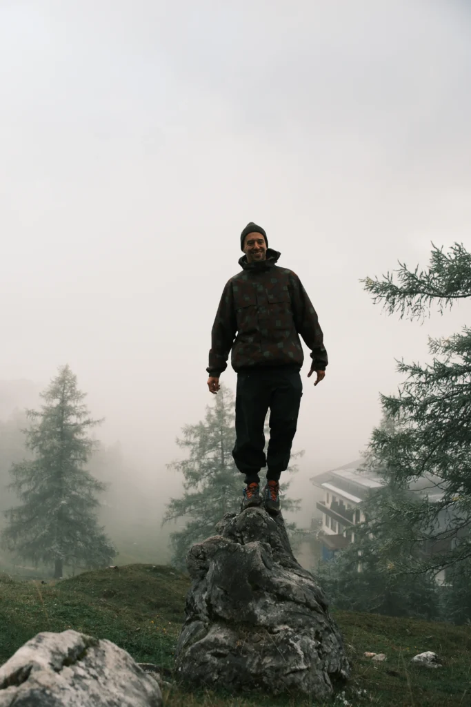Elias standing on a rock among trees in mountain mist.