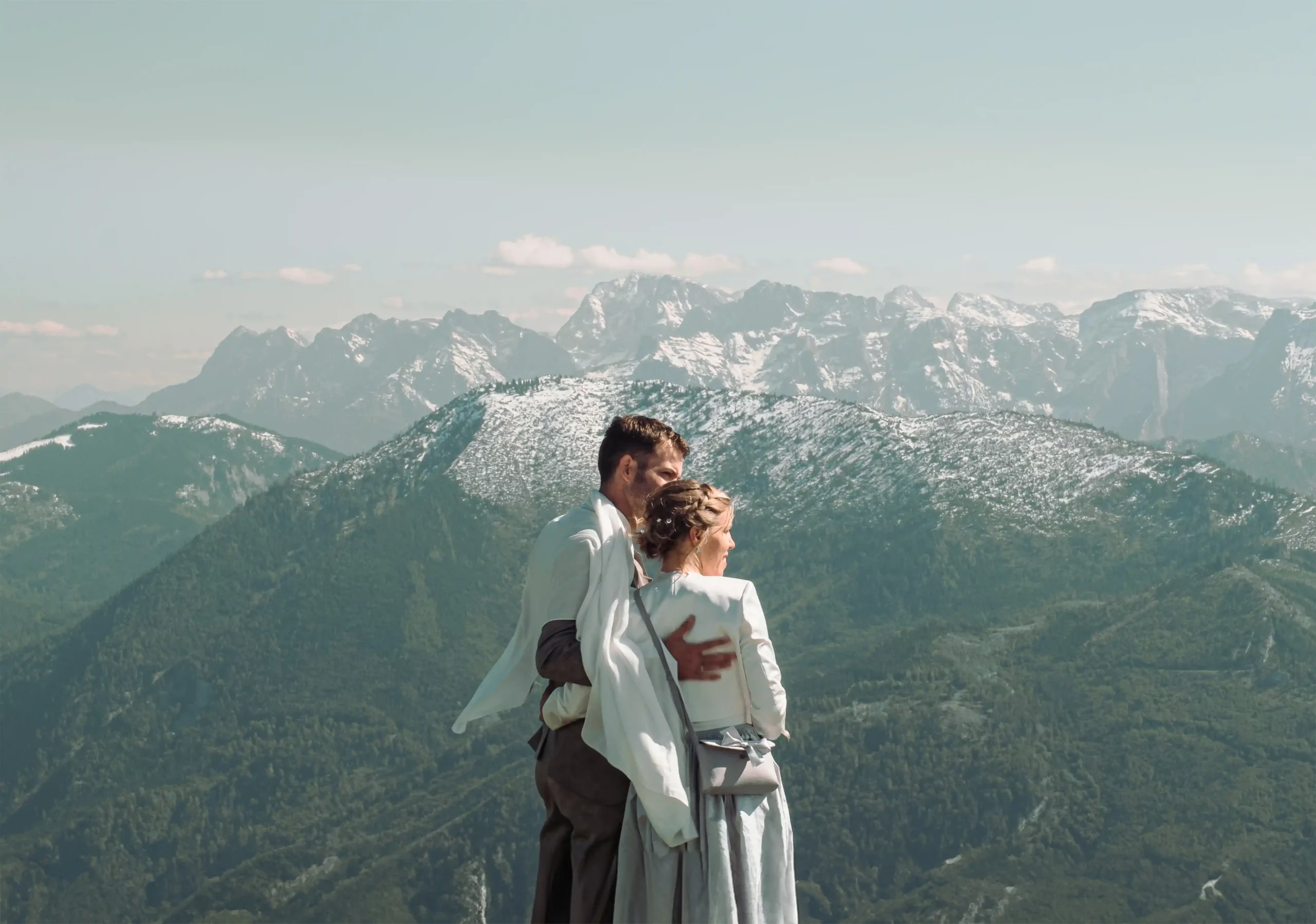 Paar umarmt sich, in ein Tuch gehüllt, über einem Bergtal.