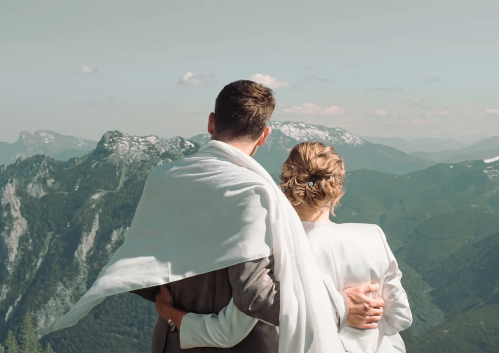 Couple looking towards the mountains with a wrap around their shoulders.