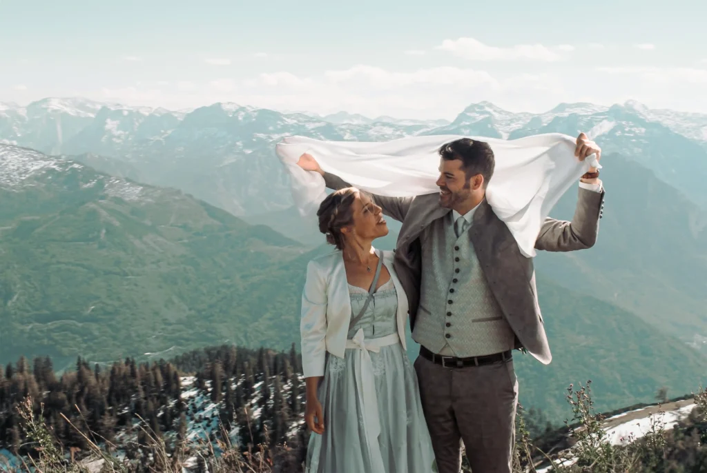 Couple holding a wrap above their heads in the mountains.