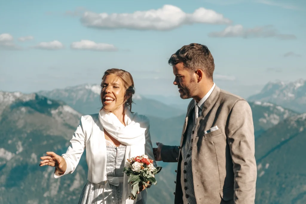 Bride laughing beside the groom in the mountains.