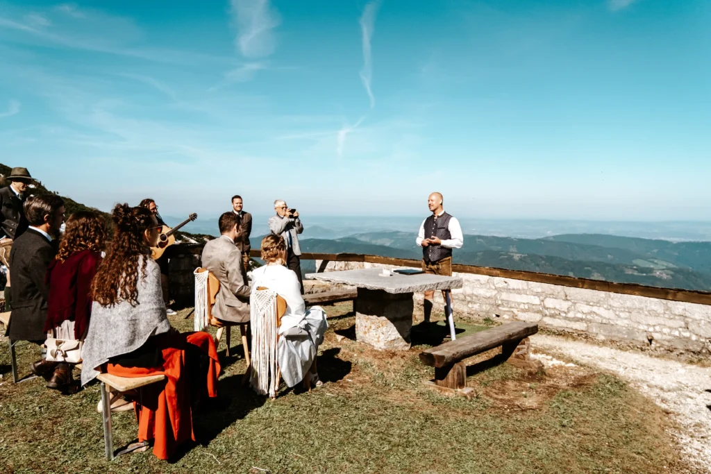 Wedding guests seated for a ceremony on a mountain terrace.