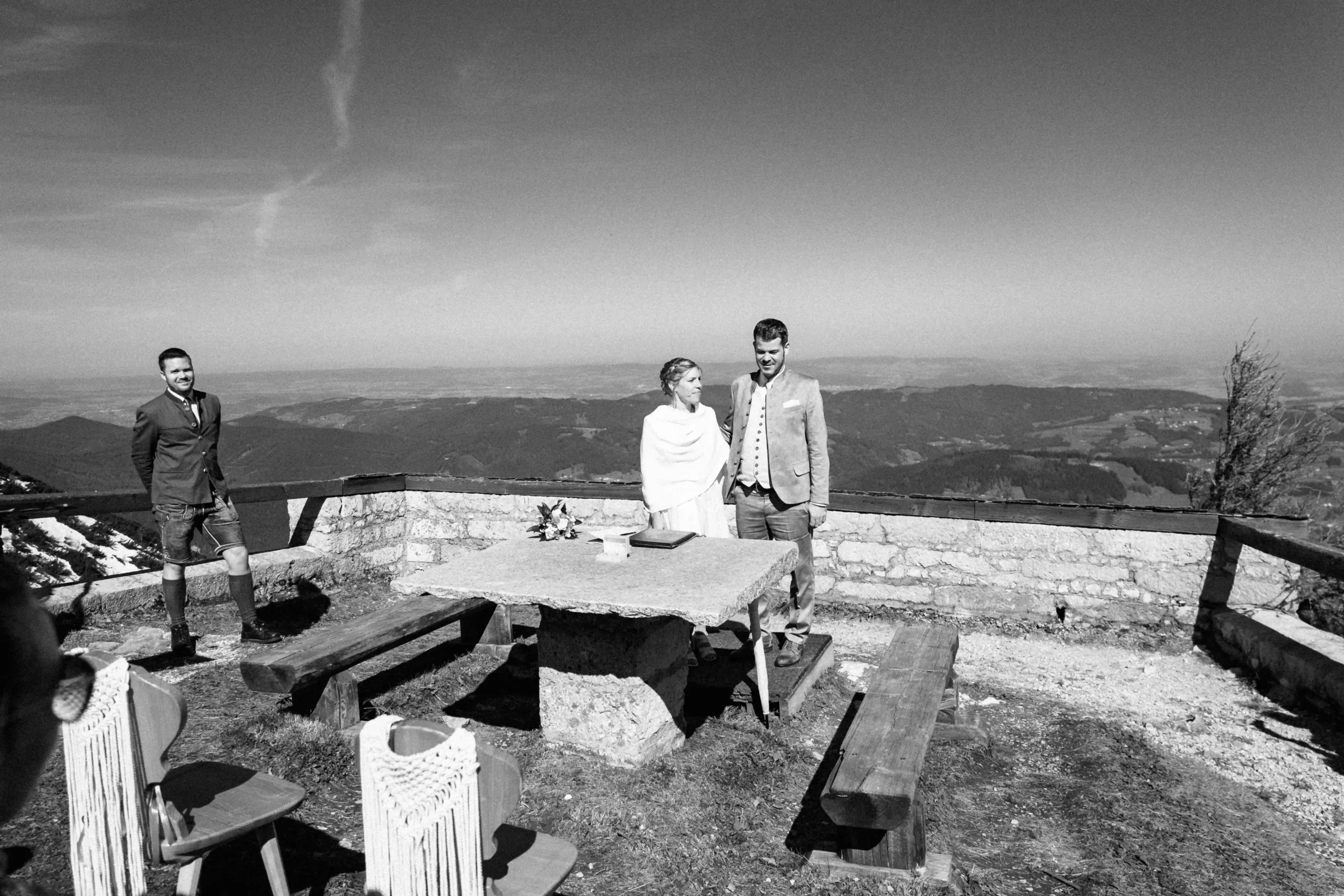 Schwarz-Weiß-Foto eines Paares am Steintisch während seiner Zeremonie.