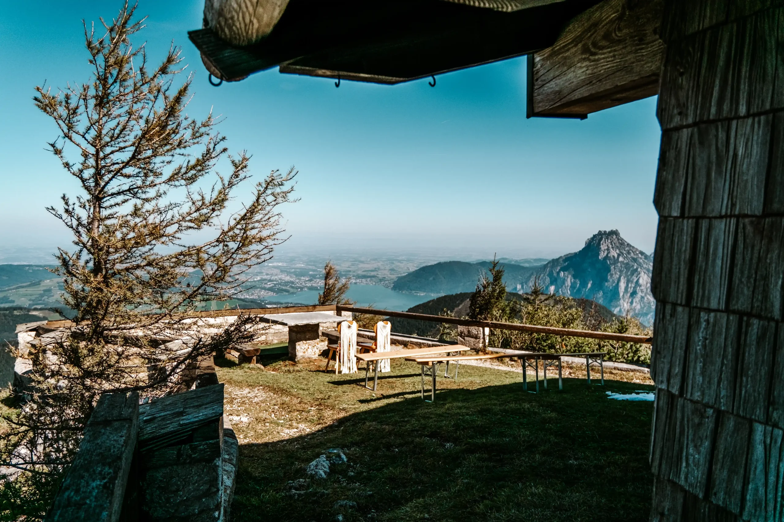 Leere Terrasse neben einer hölzernen Berghütte mit Blick auf die Gipfel.