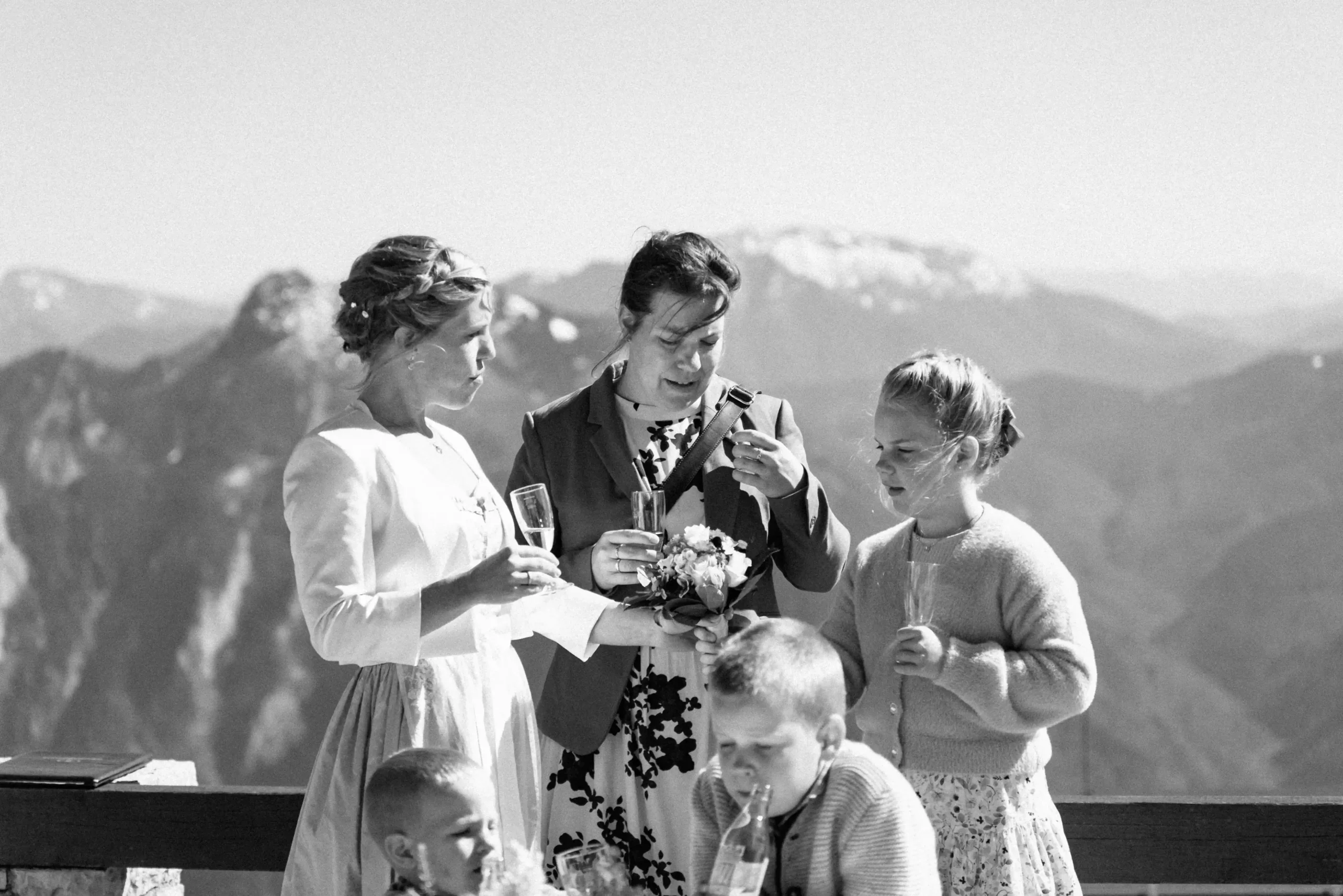 Schwarz-Weiß-Foto eines Paares, das mit einem Hochzeitsgast anstößt.