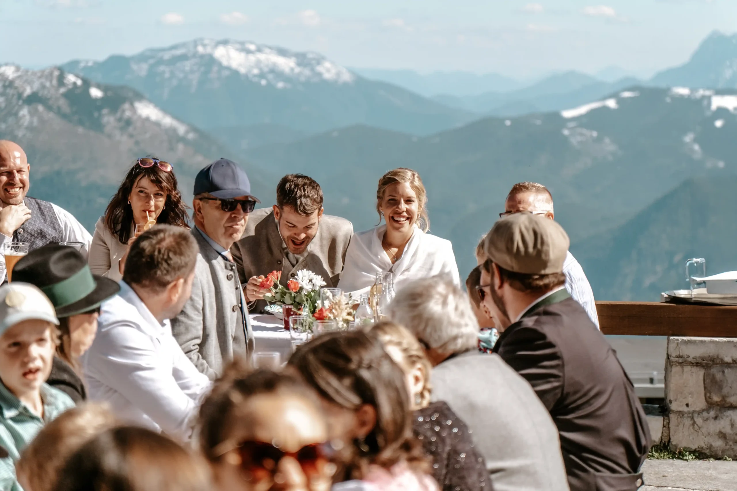 Hochzeitsgäste an einem Tisch im Freien mit Blick auf die Berge.
