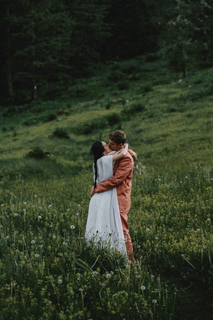 Elias and Wendy embracing on a green hillside.