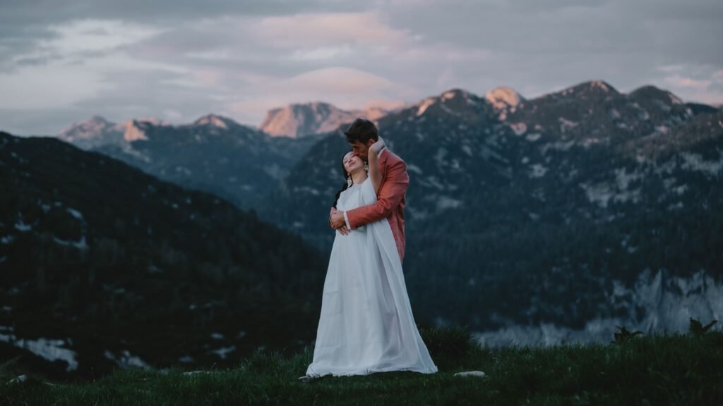 Elias and Wendy embracing above a mountain valley in the evening light.