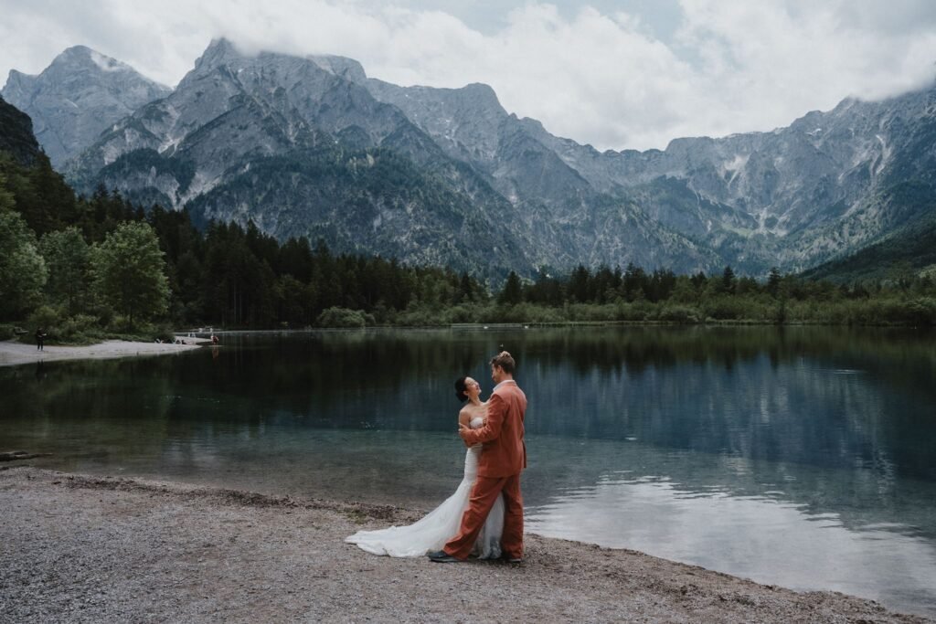 Elias and Wendy beside a lake reflecting the surrounding mountains.